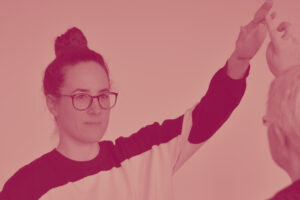 Eine junge Dame mit haelt einen Vortrag. Sie traegt eine Brille und schaut konzentriert in Richtung Publikum.