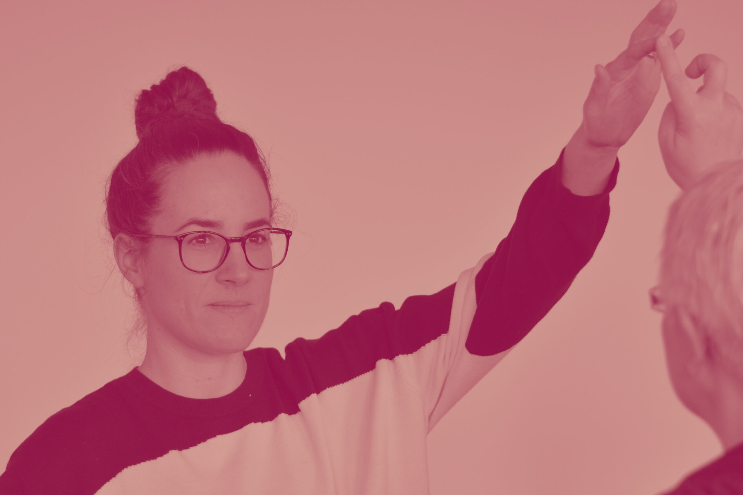 Eine junge Dame mit haelt einen Vortrag. Sie traegt eine Brille und schaut konzentriert in Richtung Publikum.
