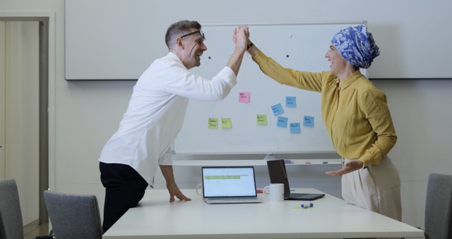 Vom Kollegen zum Vorgesetztenorgesetzten Mann und Frau reichen sich vor einem Whiteboard die Hand.