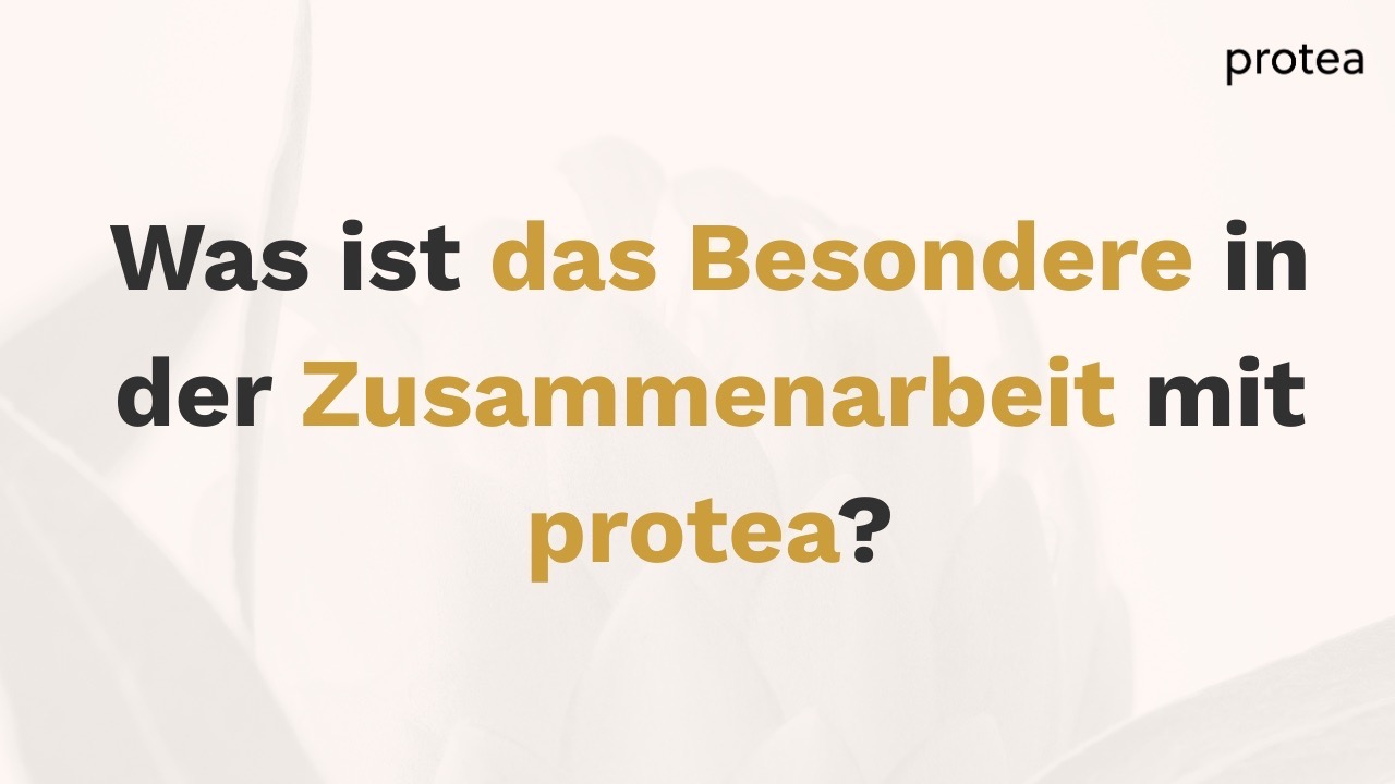 Ein Mann und eine Frau machen High Five über einen Arbeitstisch hinweg und lachen dabei. 
