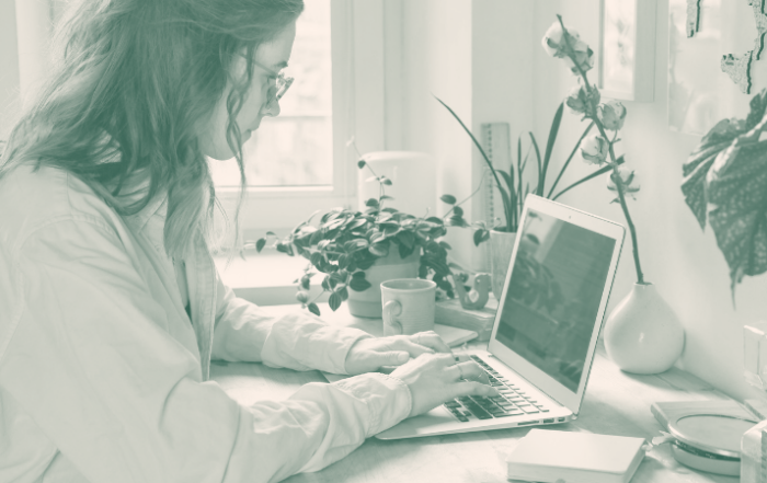 Person arbeitet konzentriert am Laptop im Home Office mit Pflanzen im Hintergrund.